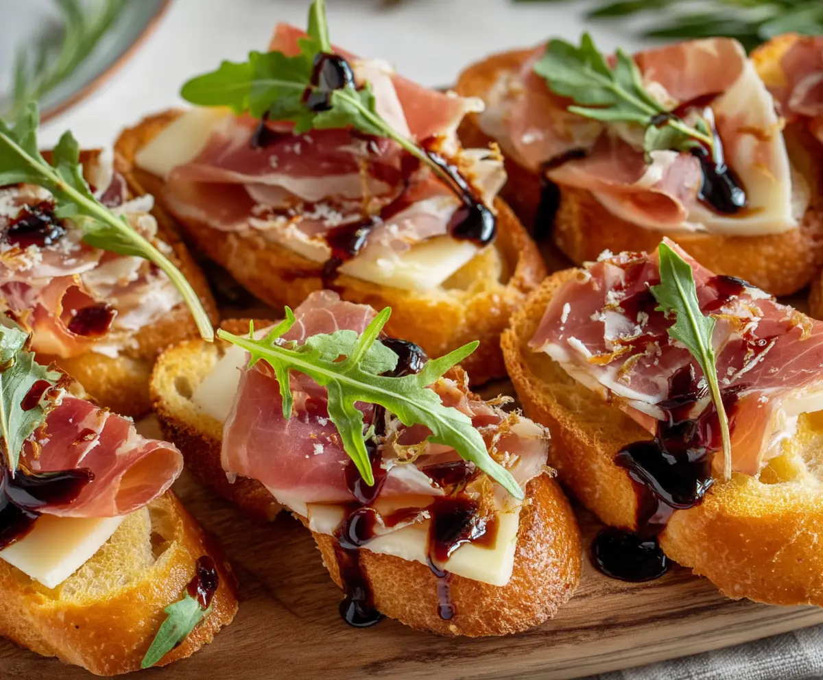 Delicious Brie and Prosciutto Crostini served on a rustic wooden board, perfect for appetizer parties.