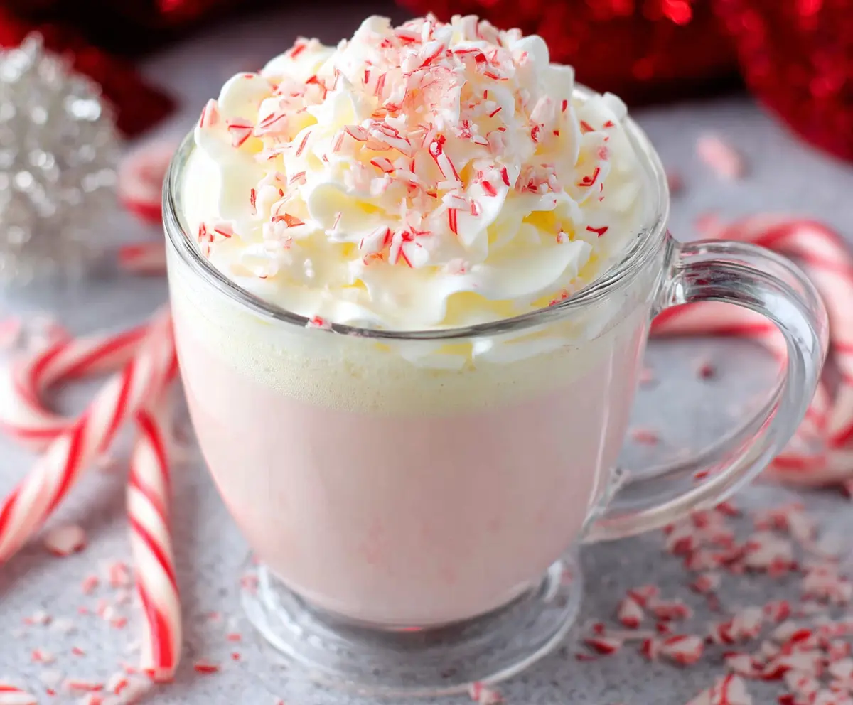 Creamy Crockpot Candy Cane White Hot Chocolate garnished with whipped cream and peppermint candies.