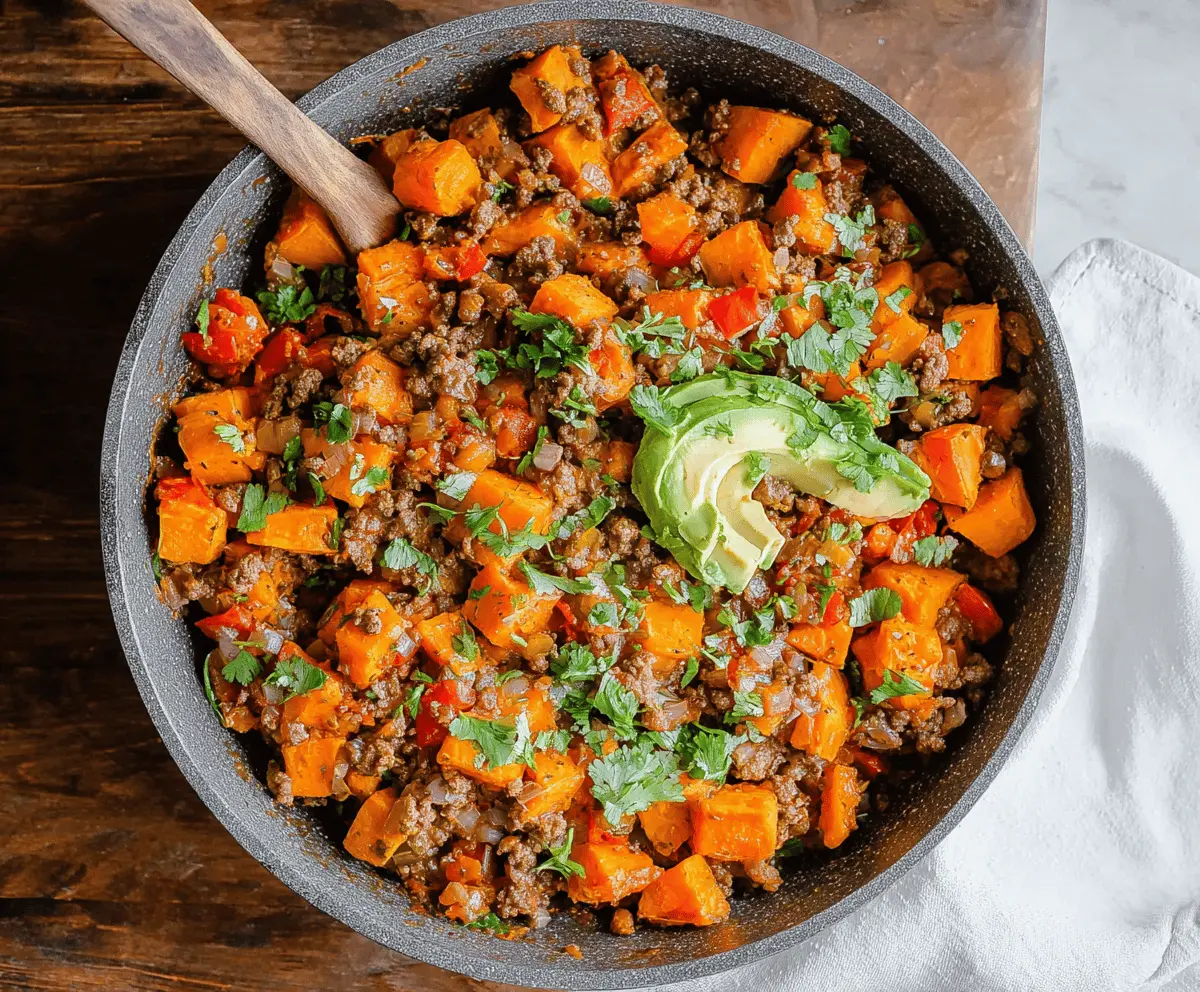 Delicious sweet potato and ground beef skillet topped with fresh herbs in a skillet dish.