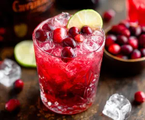 Refreshing cranberry vodka cocktail served in a glass with fresh cranberries and a citrus slice