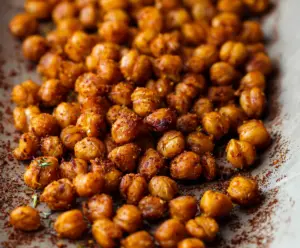 Crispy roasted chickpeas garnished with herbs on a white plate, perfect healthy snack