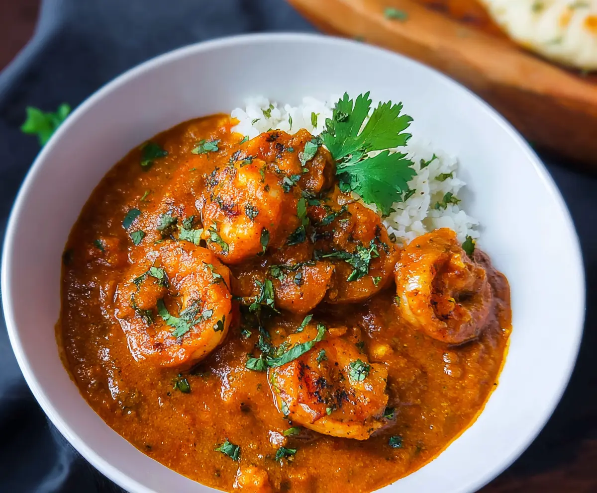 Delicious shrimp tikka masala served with cilantro garnish on a white plate.