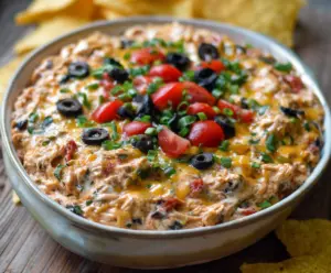 Delicious chicken taco dip layered with cheese, lettuce, and salsa, perfect for parties.