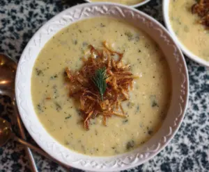 Delicious Ina Garten roasted potato and leek soup served in a bowl, showcasing a creamy texture and fresh herbs on top.