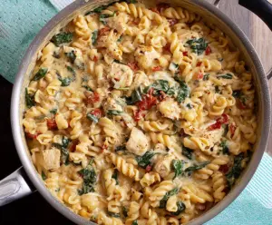 Creamy One Pot Tuscan Chicken Pasta with sun-dried tomatoes and spinach in a rustic skillet.
