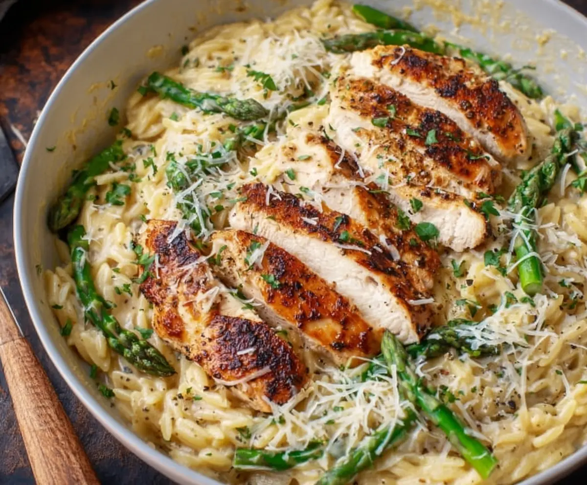 Delicious Parmesan Orzo with tender chicken and fresh asparagus on a plate.