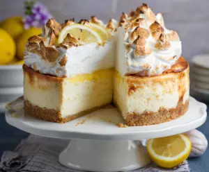 Delicious Triple Lemon Meringue Cheesecake topped with golden meringue and fresh lemon slices.