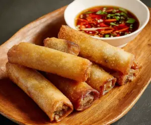Crispy Beef Lumpia served with dipping sauce on a plate