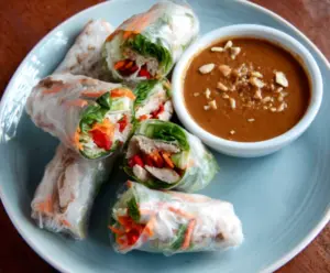 Delicious pork spring rolls served with a peanut lime dipping sauce, perfect for appetizers or light meals.